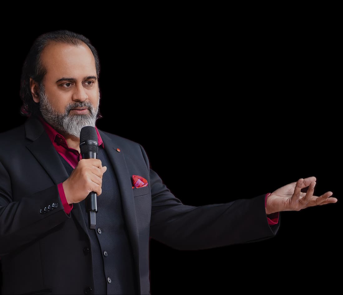 Acharya Prashant speaking into a microphone with his hand extended